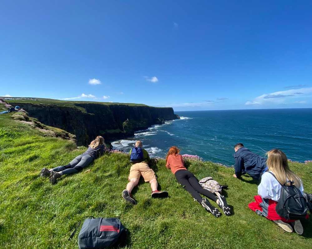 Group of tourist laying looking over cliffs of Moher