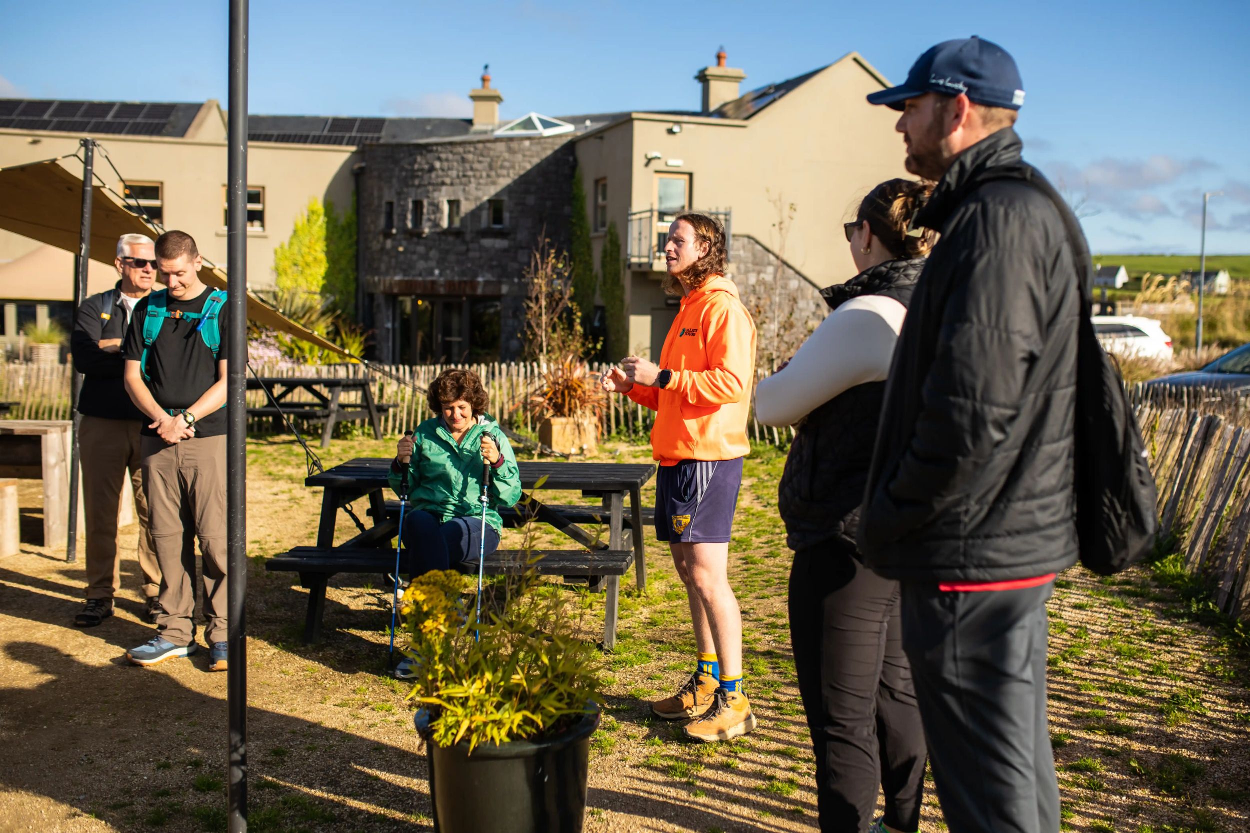Outdoor gathering with people in bright clothing at a community center garden on a sunny day.