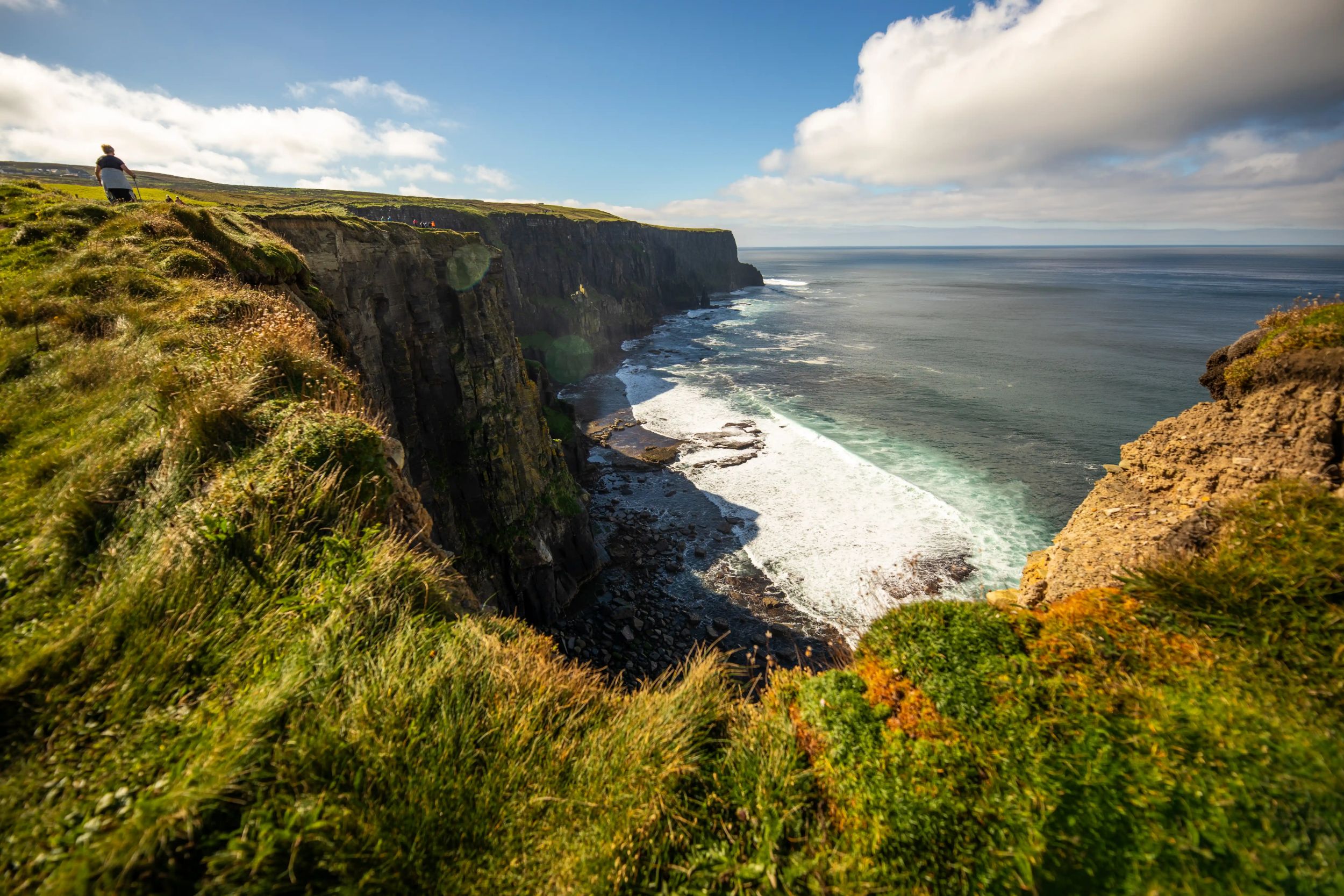 Breathtaking view of the Cliffs of Moher, Ireland, with lush green landscape and waves crashing against the rocky coastline.