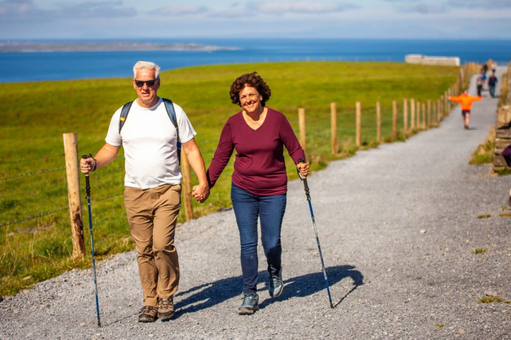 AKphoto (182) Senior couple hiking on a scenic coastal path, holding hands and enjoying the sunny day.