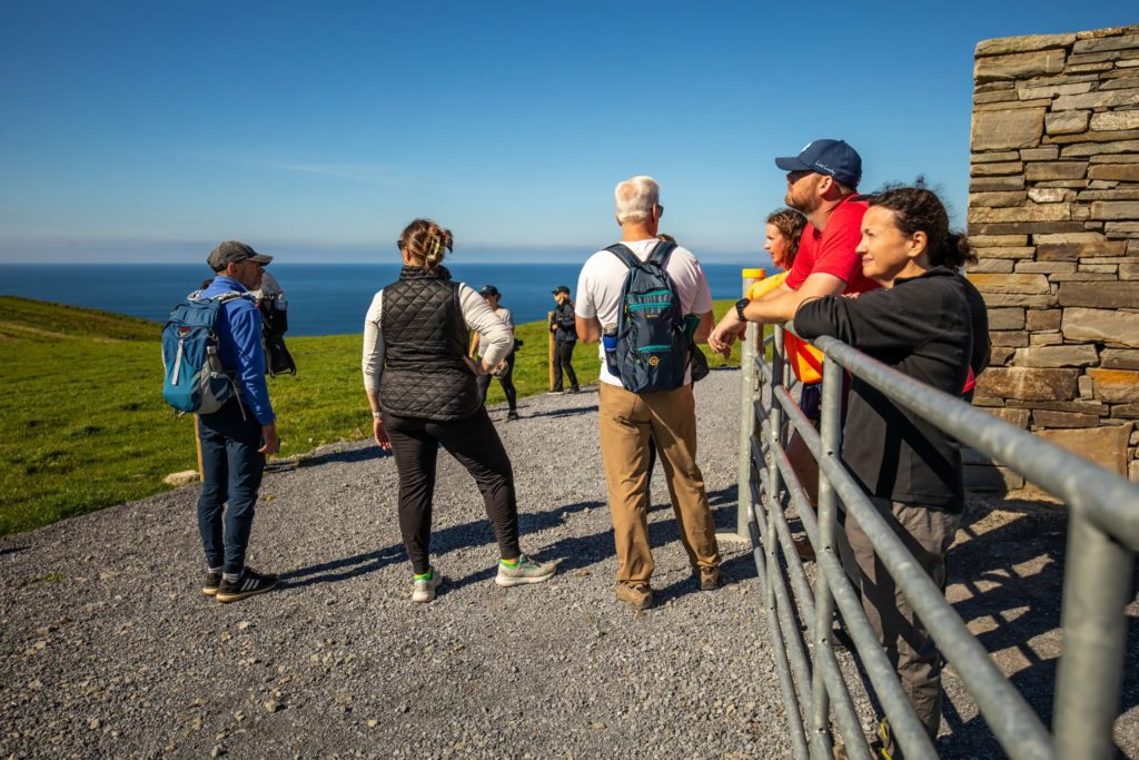 AKphoto (185) Group of hikers enjoying scenic ocean views on a sunny day from a hilltop trail.