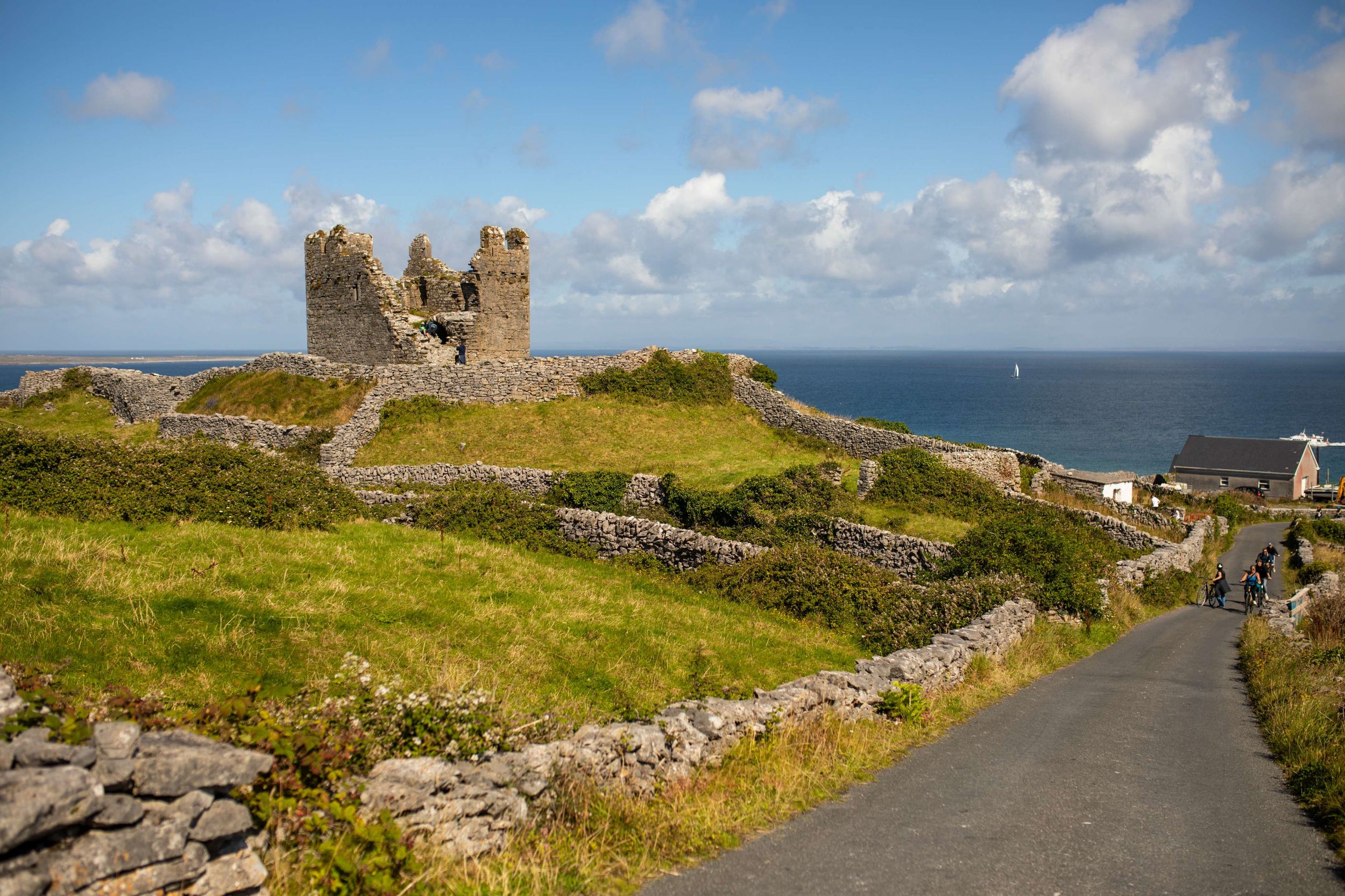 Scenic view of Dun Aengus fort on Inishmore, Aran Islands, surrounded by stone walls and ocean under a blue sky.