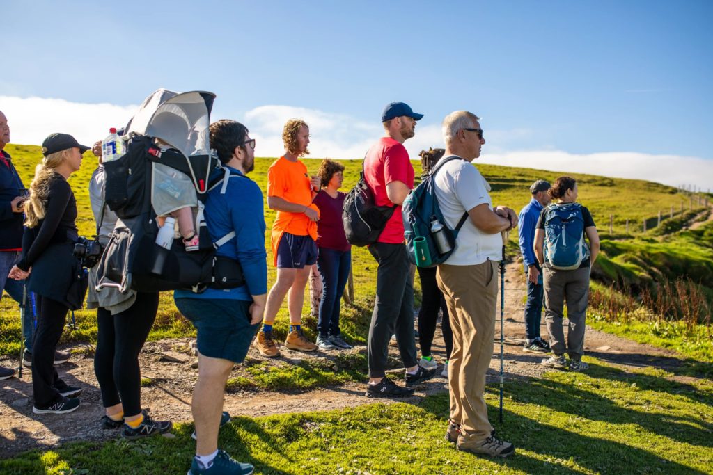 AKphoto (46) Group of hikers enjoying a scenic walk in the countryside on a sunny day, surrounded by lush green hills.