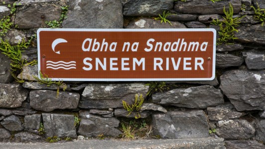 a sign on a rock next to a brick wall